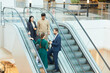 © Seventyfour - Wide angle view at group of business people standing on escalator in office building and communicating, copy space