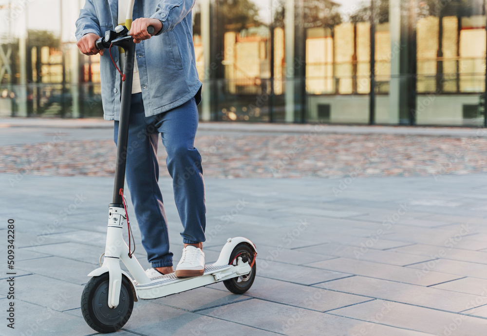 Man riding his e-scooter on the city street Stock Photo | Adobe Stock
