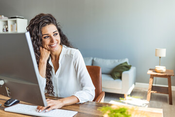 Portrait of young smiling woman looking at camera. Happy girl seating in creative office. Successful businesswoman. Modern business woman.