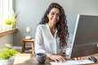 © Dragana Gordic - Successful businesswoman standing in creative office and looking at camera. Young latin woman entrepreneur in a coworking space smiling. Portrait of beautiful business woman