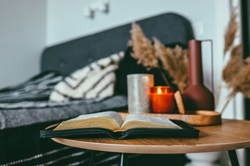 Open bible on wooden table in bedroom, scandinavian interior