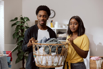 Wall Mural - A young couple in love live in a shared apartment, perform household chores, keep a wicker basket with dirty laundry sorted to be thrown into the washing machine.