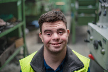 Wall Mural - Young man with Down syndrome working in industrial factory, social integration concept.