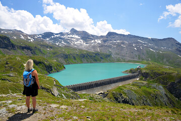 Wall Mural - Hiker by the mountain lake Lac de Goillet, Aosta valley, Italy. Summer landscape in the Alps.