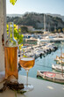 Cold rose wine in glass and bottle served on outdoor terrace in sunlights with view on old fisherman's harbour with colourful boats in Cassis, Provence, France
