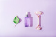 © Viktoriya - Cosmetic serum, rose quartz crystal facial roller and green leaf on purple background. Skincare, spa and wellness concept. Top view, flat lay