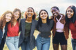 © Lomb - Cheerful multi-ethnic group of young women hugging arms on shoulders outdoors laughing, smiling and looking at the camera - youth culture lifestyle concept - only women