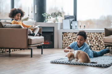 Wall Mural - A boy playing with a puppy, a girl reading a book