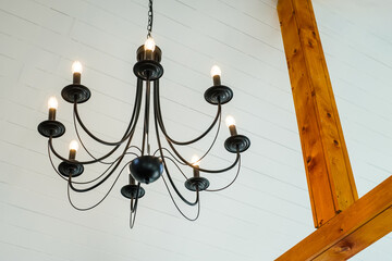 Modern electric ceiling lamp in the white room designed as old style chandelier