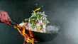 Closeup of chef throwing vegetable noodle mix from wok pan in fire.