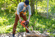 © Angelov - man sawing branches with a chainsaw. Concept of a professional logging