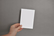 Female hand holding A5 template blank paper mockup. Invitation template