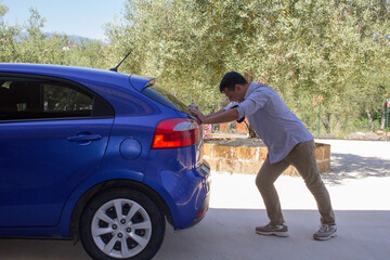 Wall Mural - Image of a man pushing his car after it broke down and ran out of gas. Reference to the current expensive fuel