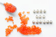 Fake red caviar eggs on a white surface next to a spoon and the inscription fake red caviar. Concept of cheating the consumer and selling counterfeit food products.