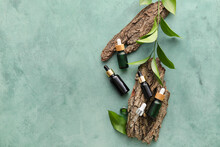 Bottles Of Natural Serum, Tree Barks And Plant Leaves On Green Background