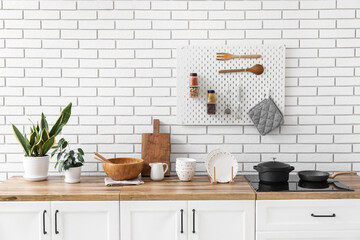 Wall Mural - Counters with kitchen utensils, stove and houseplants near white brick wall