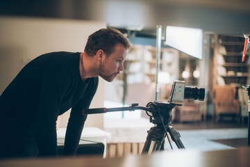 Director of photography with a camera in his hands on the set. Professional videographer at work on filming a movie, commercial or TV series.