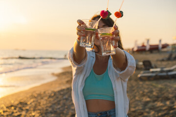 Portrait of a happy young girl with a cocktail in hand on a background of beautiful sea. Girl having fun on summer vacation. Freedom and happiness