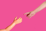 Fototapeta Kwiaty - Child's hand extends a finger to the hand of a plastic doll. The Creation of Adam.