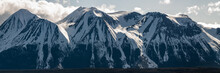 Panoramic Shot Of Snow Capped Mountain View Scenery Seen In Northern British Columbia During Spring Time With Blue Sky Day And Clouds.