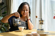 © bongkarn - Cheerful Asian aged-woman brewing her morning coffee in the house