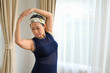 © bongkarn - Portrait attractive aged woman exercising with weights arms up, doing yoga, stretching arms