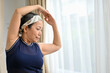 © bongkarn - Healthy asian middle aged woman exercising, doing yoga, stretching her arms