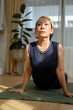 © bongkarn - Asian aged woman doing easy pilates at home, stretching her body on yoga mat.