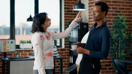 Fototapeta brain dead zombie woman touching businessman while discussing. doomsday survivor talking with dangerous dead walking corpse having bloody and deep wounds in office workspace.