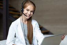 Smiling Woman With Headset And Laptop Looking At The Camera. Remote Work As A Mobile Operator, Support Service.