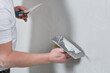 the master holds a spatula with a mortar in his hand, applying decorative plaster to the wall