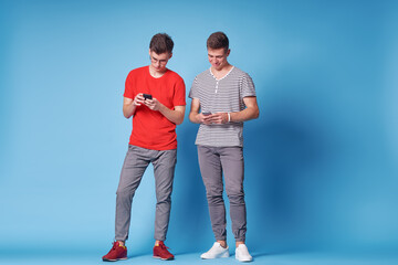 Wall Mural - Youth and technology. Young happy friends using smartphone together. Blue background.