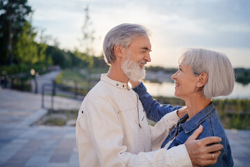 Wall Mural - Outdoors portrait of happy elderly couple embracing in summer park.