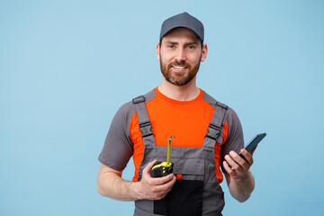 Wall Mural - Man builder in uniform talk on mobile phone and holding a tape measure. Studio shoot