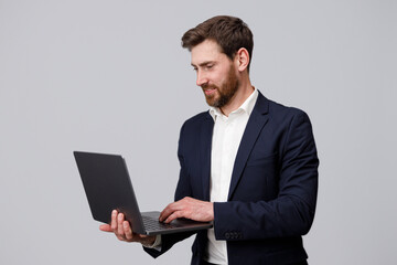 Sticker - Handsome man in suit working online on laptop over grey studio background