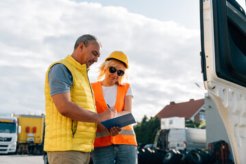 Wall Mural - Mature woman and man at cargo warehouse, truck drivers delivery inspection 