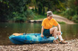 © _KUBE_ - A young dissatisfied woman is sitting on a kayak and scratching her pimpled leg from a mosquito bite. The concept of camping and World Tourism Day