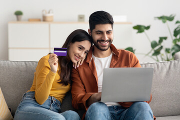 Wall Mural - Couple Shopping Online Making Payment With Card Using Laptop Indoors