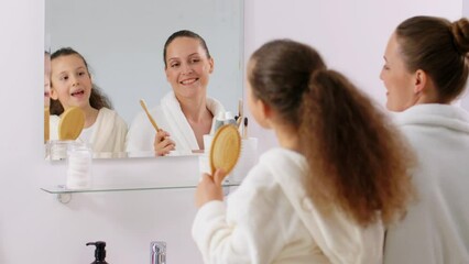 Sticker - beauty, hygiene and people concept - happy smiling mother and daughter with hairbrush and toothbrush singing in bathroom