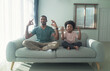African American dad and little son calm down do practicing yoga exercises with closed eyes sit on sofa in living room. Black Family sit on couch in lotus pose position meditation together at home.