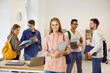 © Studio Romantic - Portrait of happy female student in classroom on background of multiracial classmates. Girl with notebooks and backpack looks at camera. Concept of learning in high school, university or college.