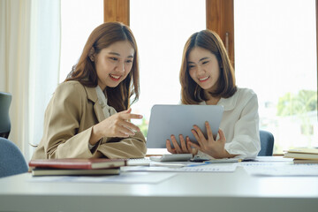 Wall Mural - Negotiation, Analysis, Discussion, Portrait of an Asian women economist and marketer using tablet computer to plan investments and financial to prevent risks and losses for the company