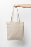 Fototapeta  - Female hand holding eco or reusable shopping bag against white background