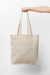 female hand holding eco or reusable shopping bag against white background