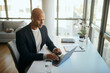© Drazen - Smiling African American businessman using computer while working in the office.
