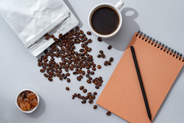 Poster - Cup of coffee with notebook on gray background top view