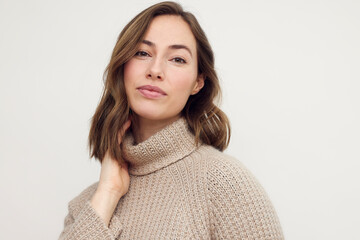 Wall Mural - Portrait of a beautiful young woman in warm sweater, posing and looking in camera.