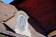baroque style roof dormer with oval window. richly decorated stucco elevation detail. steeply sloped mansard roof. blue sky. classic architecture concept. travel and tourism. beaver tail clay tiles