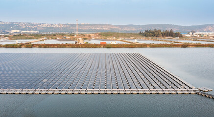 Solar farm panels in aerial view, rows array of polycrystalline silicon solar cells or photovoltaics in solar power plant floating on the water in lake, Alternative renewable energy.
