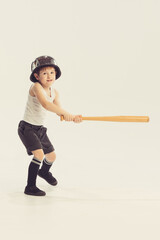 Wall Mural - Portrait of little boy, child with bat and helmet posing, playing isolated over grey studio background